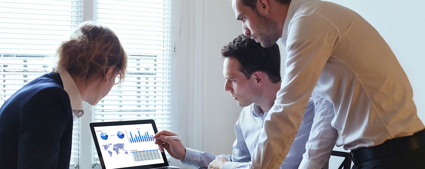 3 coworkers looking at graphs on a laptop screen