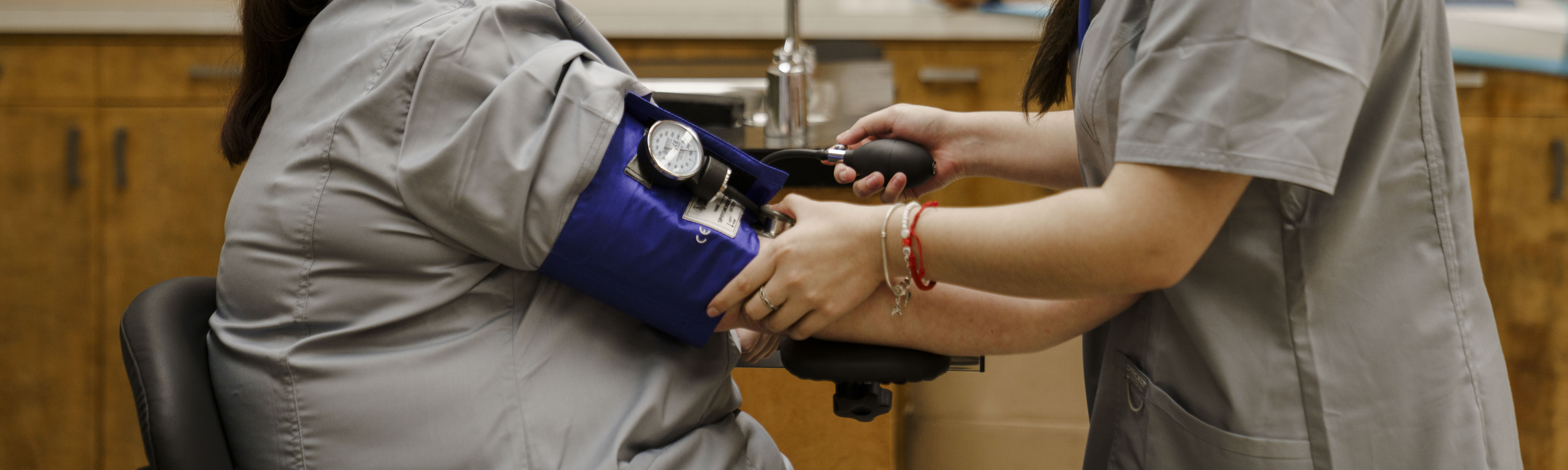 Image of two nursing students, one taking the blood pressure of the other